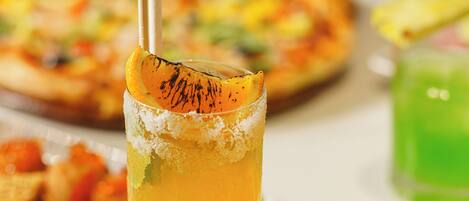 A table with a glass of orange juice, a pizza, and various dishes.