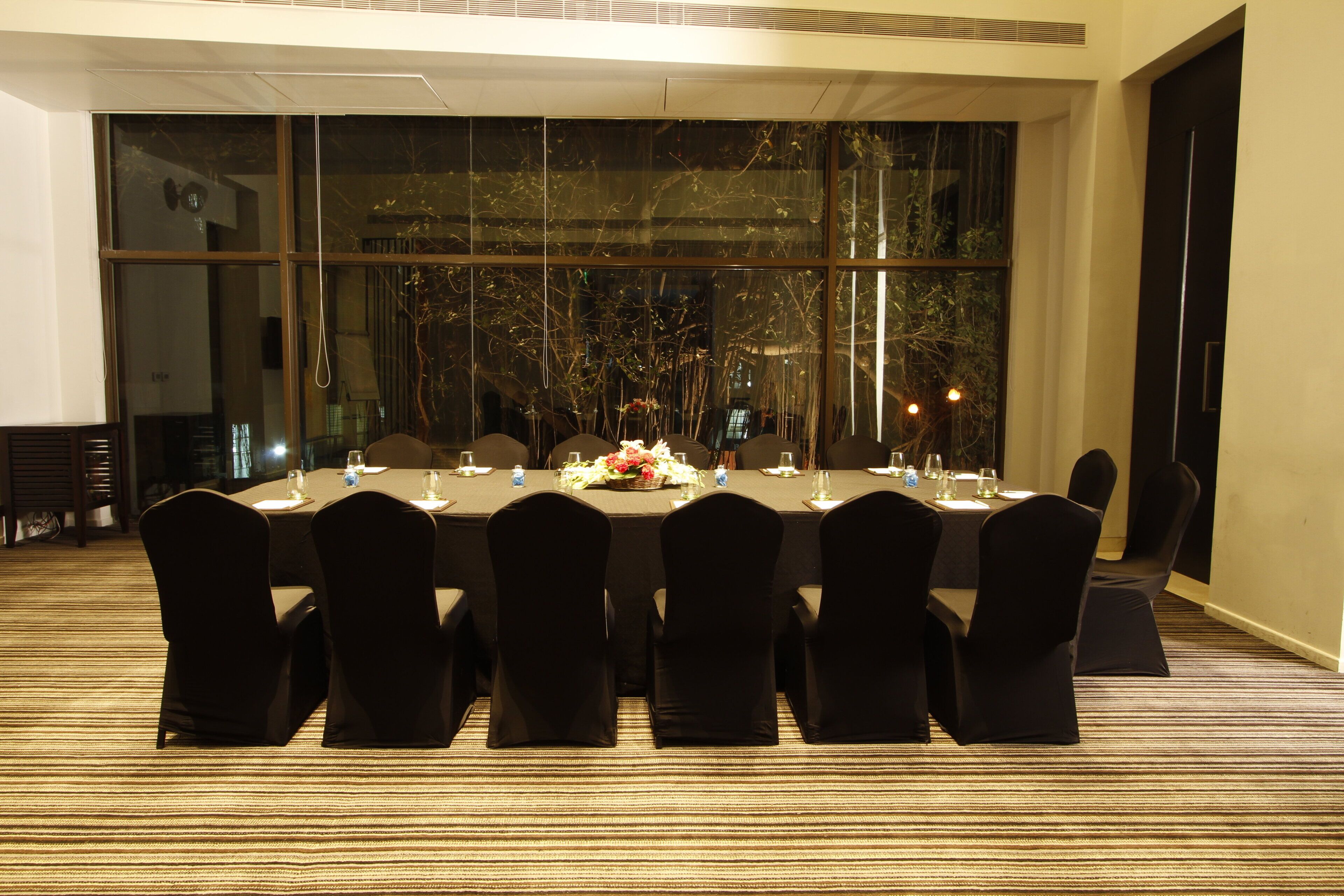 A conference room with a long table, black chairs, and a carpeted floor.