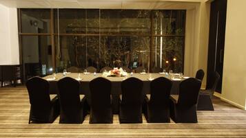 A conference room with a long table, black chairs, and a carpeted floor.