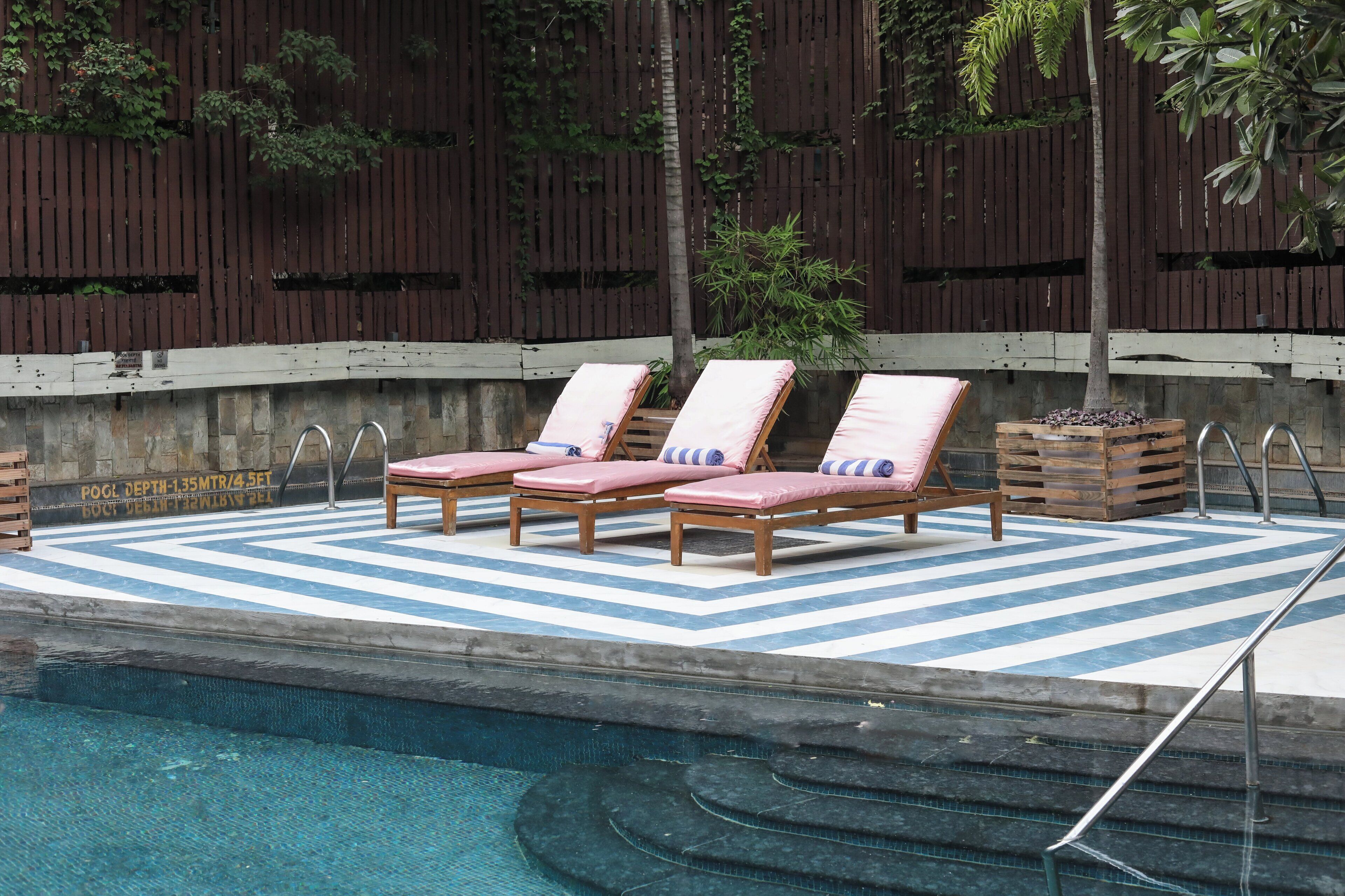 Un área de piscina con sillones de descanso y una terraza de madera.