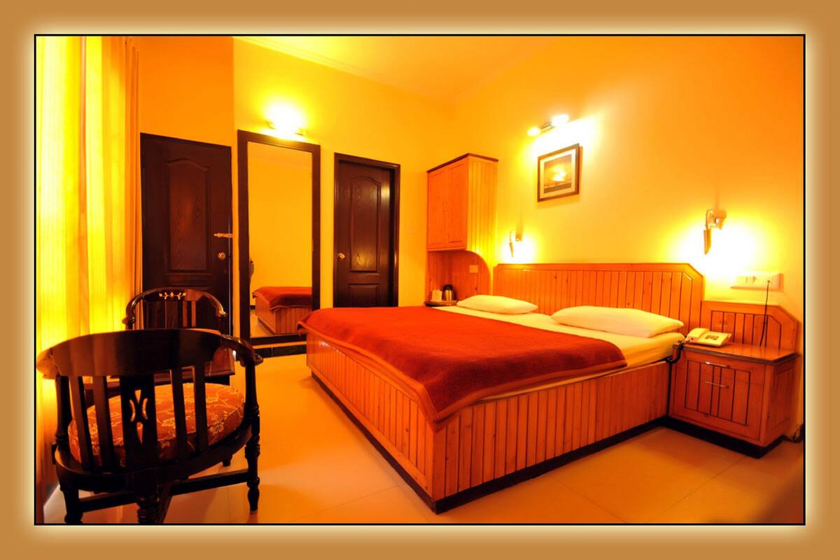 A hotel room with a bed, a chair, a nightstand, and a door.