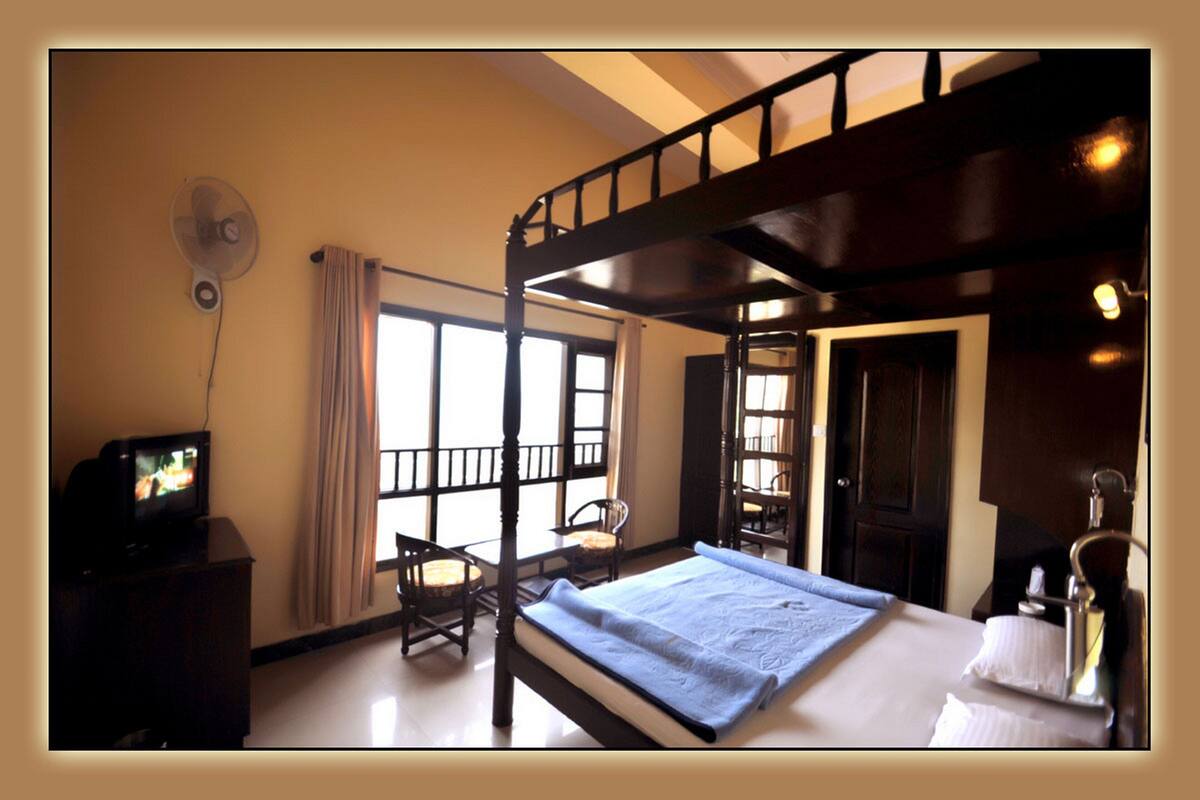 A room with a bunk bed, a television on a dresser, and a fan on the wall.