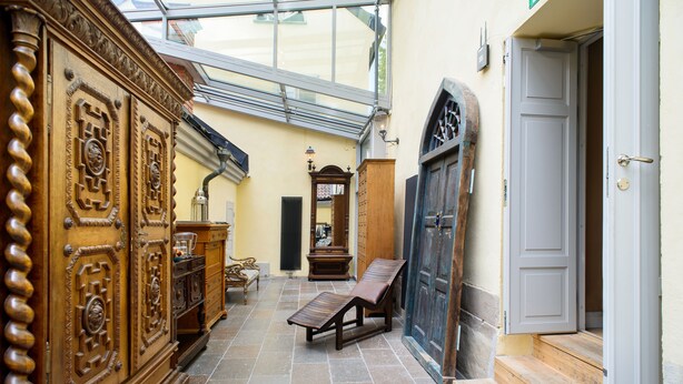 Un interior con un banco de madera, una puerta y una zona con ventanas.