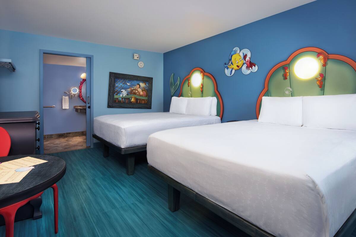 A hotel room with two beds, a desk, and a chair. There is a painting on the wall and a clock.