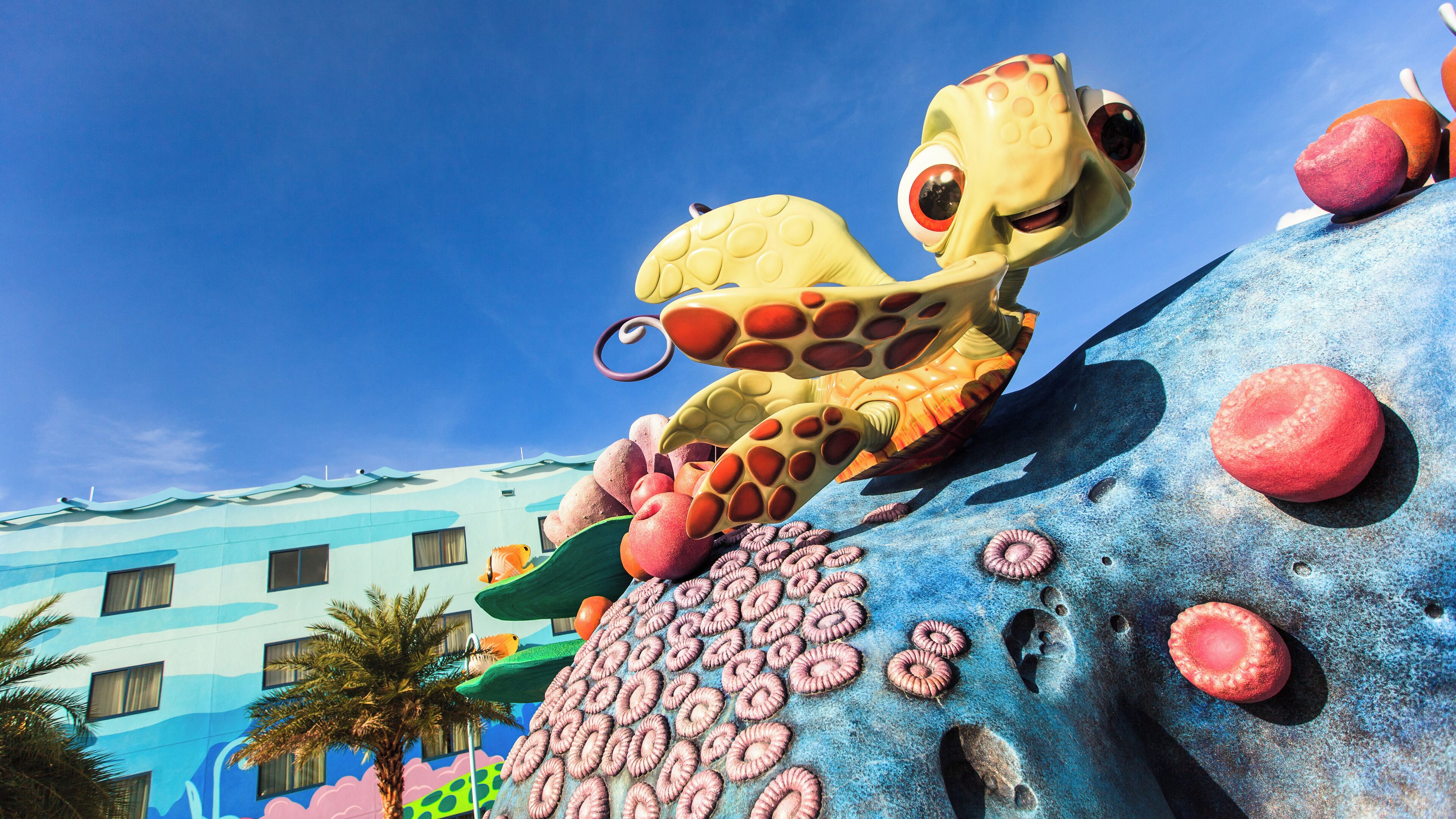 Un edificio colorido con un diseño arquitectónico único, que presenta una gran escultura de pulpo sobre una roca.