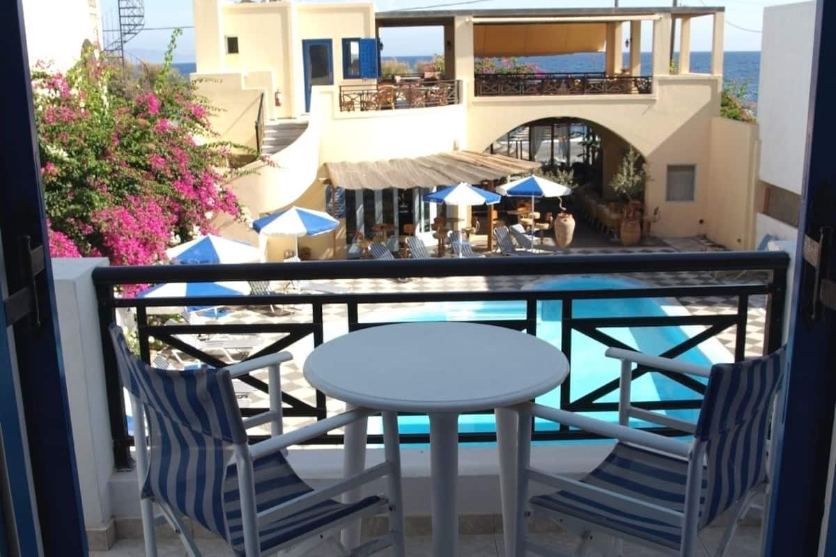 Uma varanda com piscina, duas cadeiras e uma mesa.