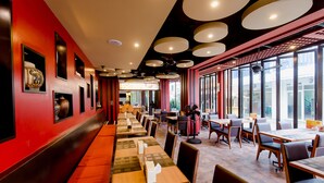 A restaurant with long communal tables, red walls, and large windows. - Aspery Hotel (Patong)