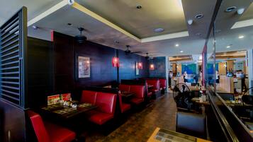 A restaurant with booths and tables, ceiling lights, and a counter area.