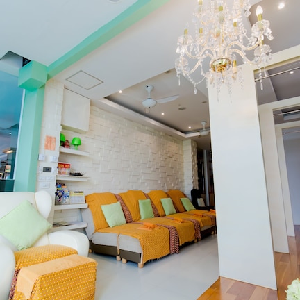 A modern hotel room with a sofa set, a chandelier, and a wall-mounted shelf with toiletries.