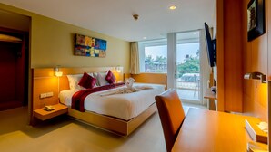 A hotel room with a bed, bedside table, and a desk with a chair. There is a window with a view of the outdoors. - Aspery Hotel (Patong)