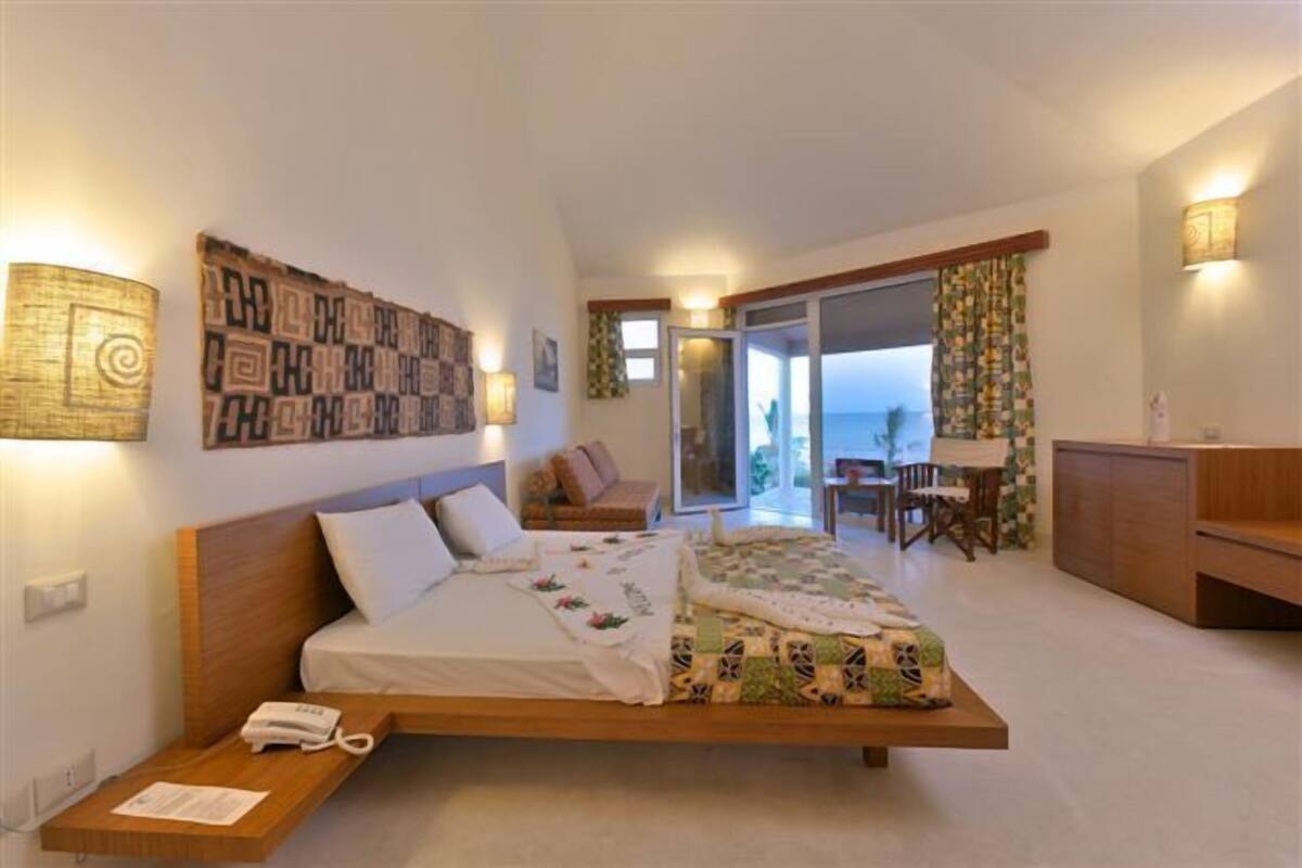 A modern bedroom with a bed, bedside table, and a view of the balcony.