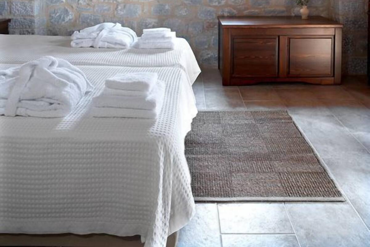 A stone-walled bedroom with a bed, a small table, and a window.