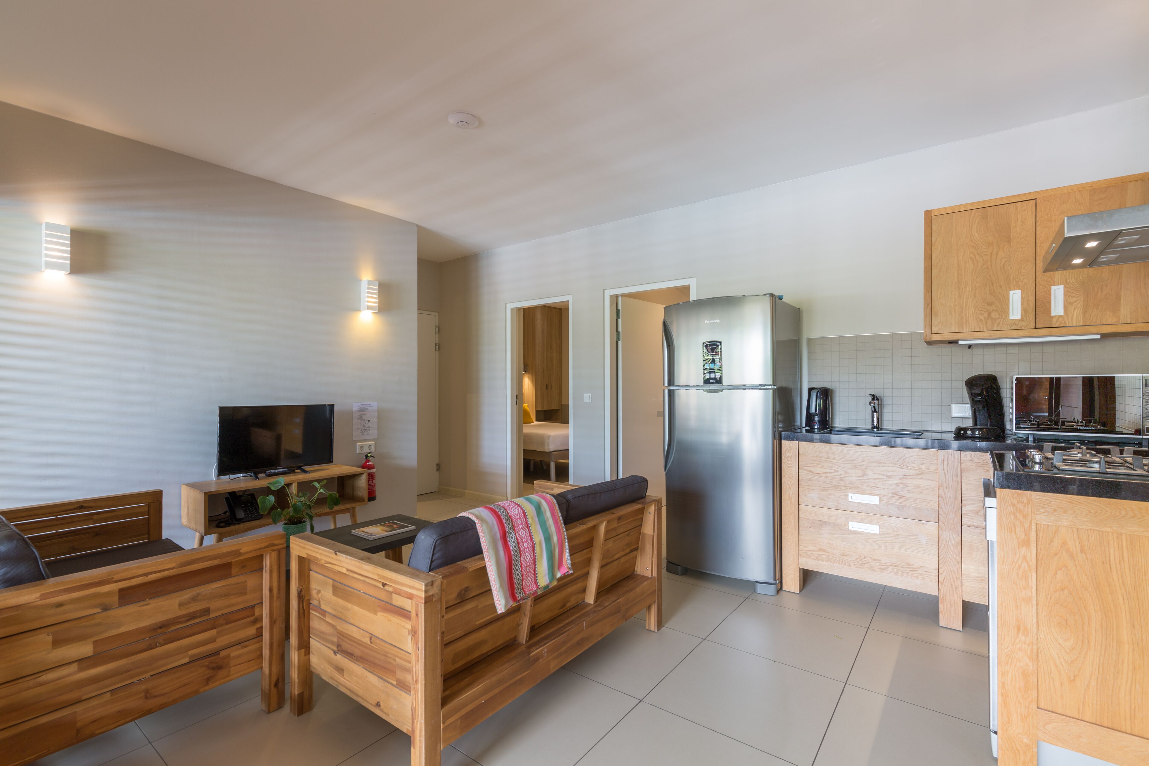 A modern kitchen with wooden cabinetry, a built-in refrigerator, and a dining area with a bench.