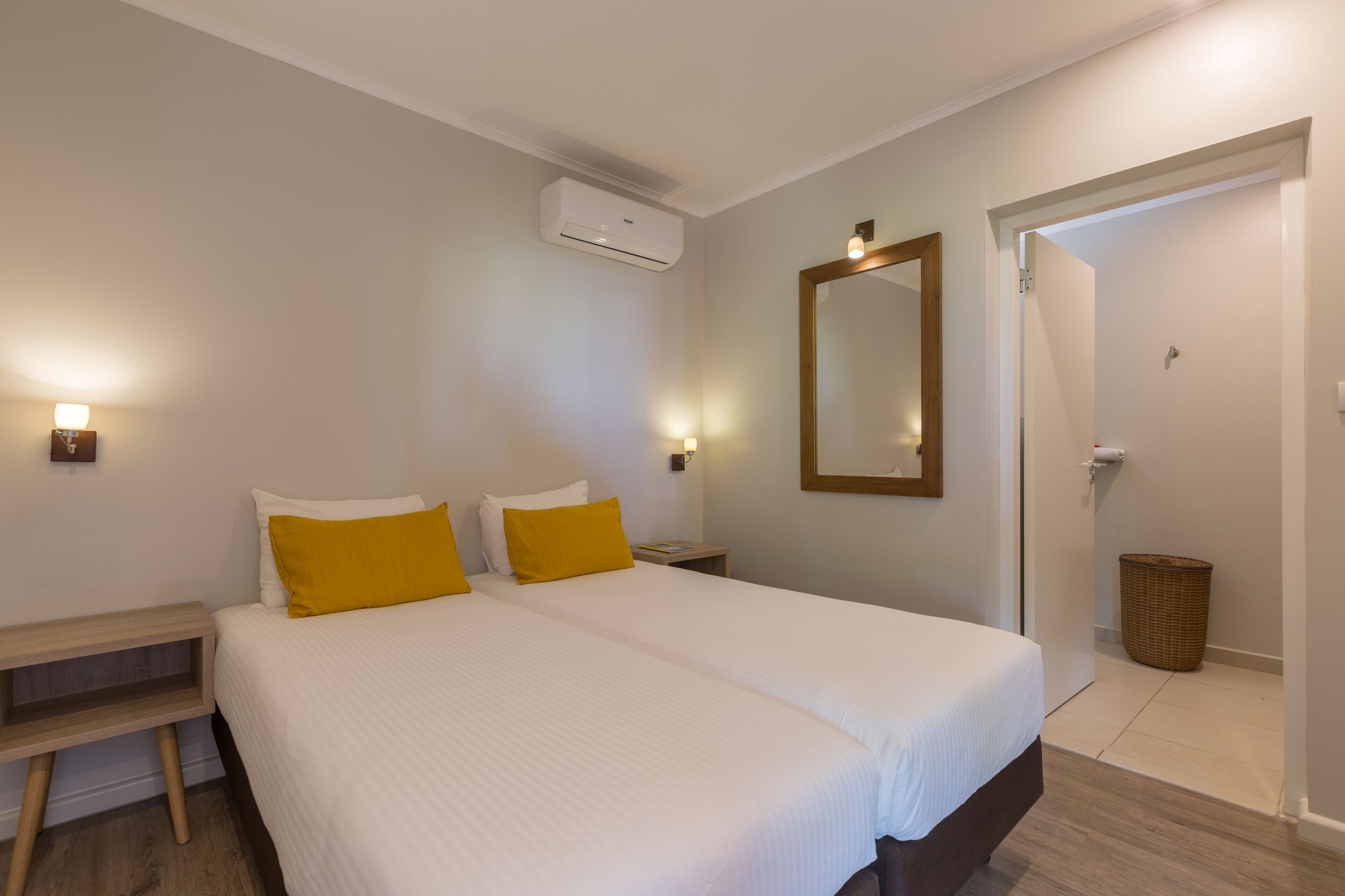 Ein Hotelzimmer mit einem großen Bett, zwei Nachttischen, einem Schreibtisch und einem Spiegel an der Wand.