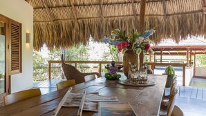 A wooden dining table with newspapers, a pen, and a vase with flowers. - Morena Resort (Jan Thiel)