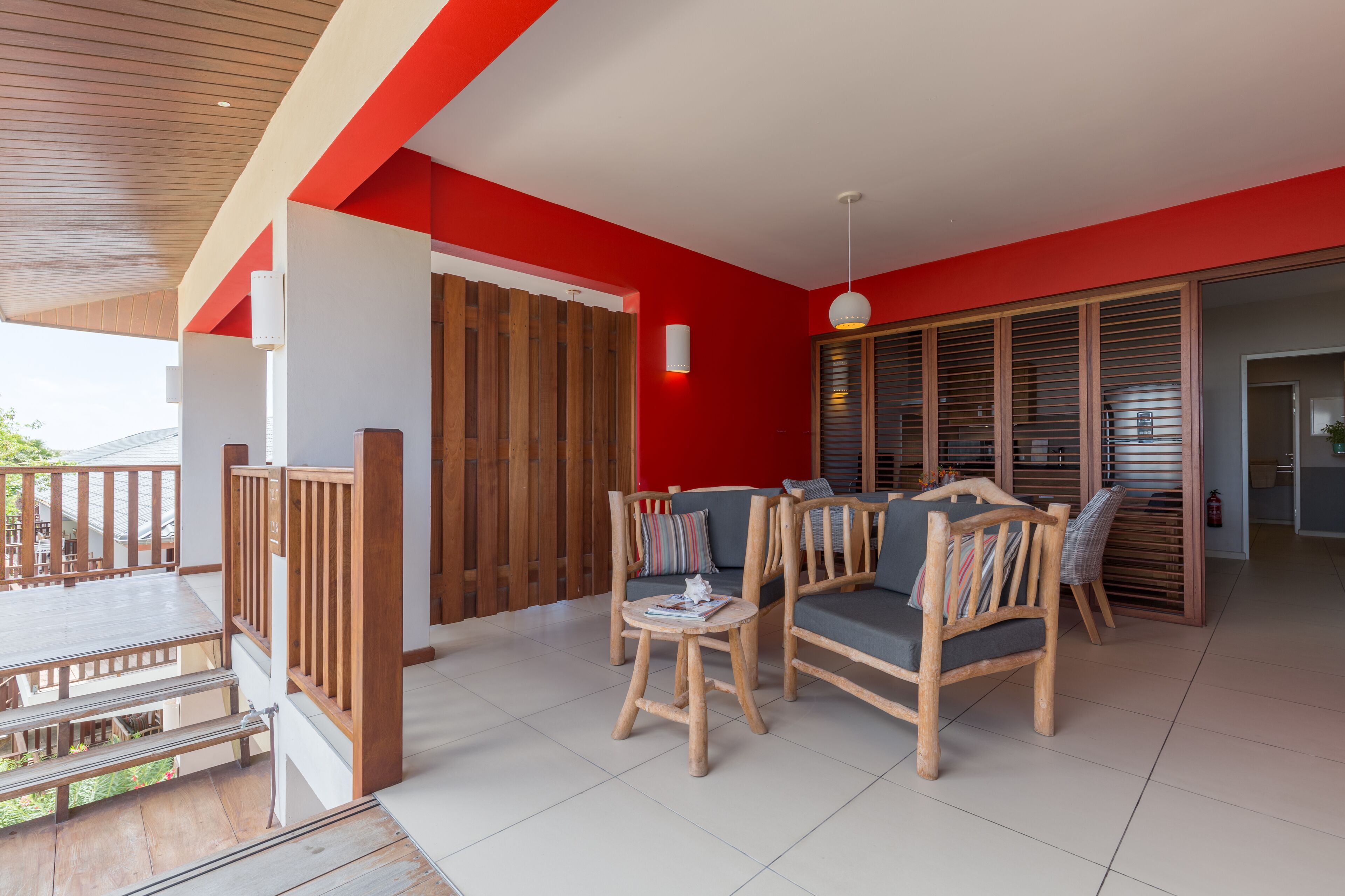A spacious outdoor seating area with wooden furniture and a red accent wall.