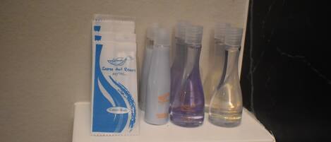 A bathroom shelf with a packet of cotton buds and three bottles of liquid soap.