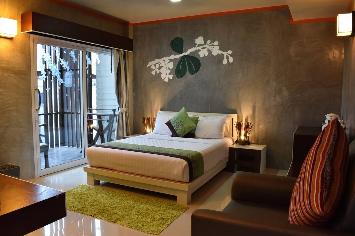 Ein modernes Schlafzimmer mit einem großen Bett, einem grünen Teppich, einer Couch und einem Balkon mit Blick.
