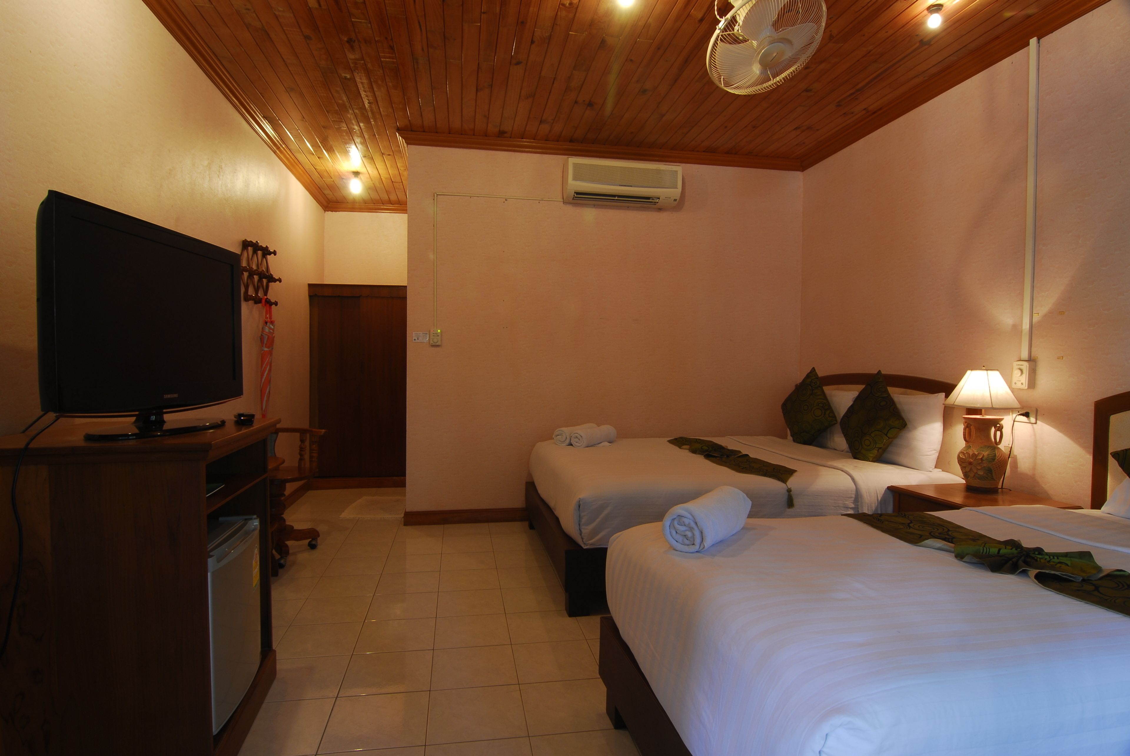 Habitación de hotel con dos camas, televisión, escritorio con computadora y aire acondicionado.