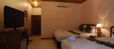 Habitación de hotel con dos camas, televisión, escritorio con computadora y aire acondicionado.