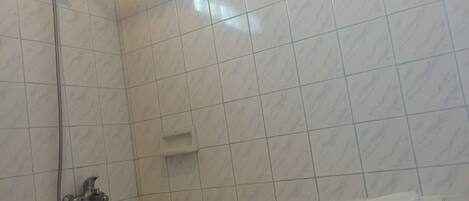 A bathroom with a bathtub, a shower, and a hand basin.