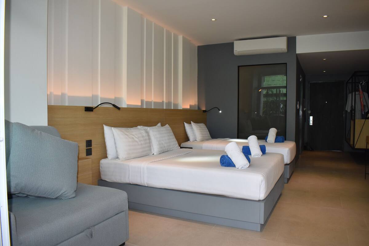 Ein modernes Hotelzimmer mit einem großen Bett, einer Sitzecke und einer Glaskonstruktion.