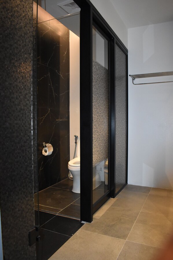 A modern bathroom with a glass-enclosed shower, a toilet, and a towel rack.