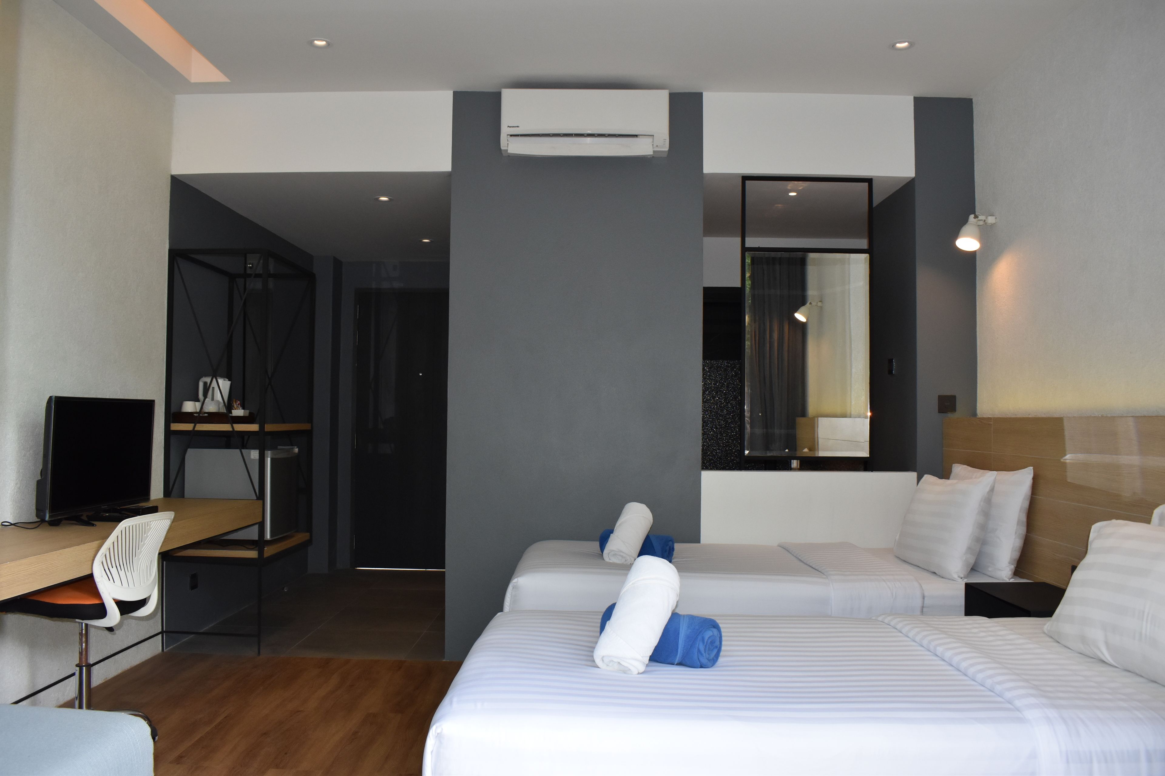 Une chambre d’hôtel moderne équipée de deux lits, d’un bureau et d’un ordinateur.