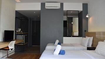 Una habitación de hotel moderna con dos camas, un escritorio y una computadora.
