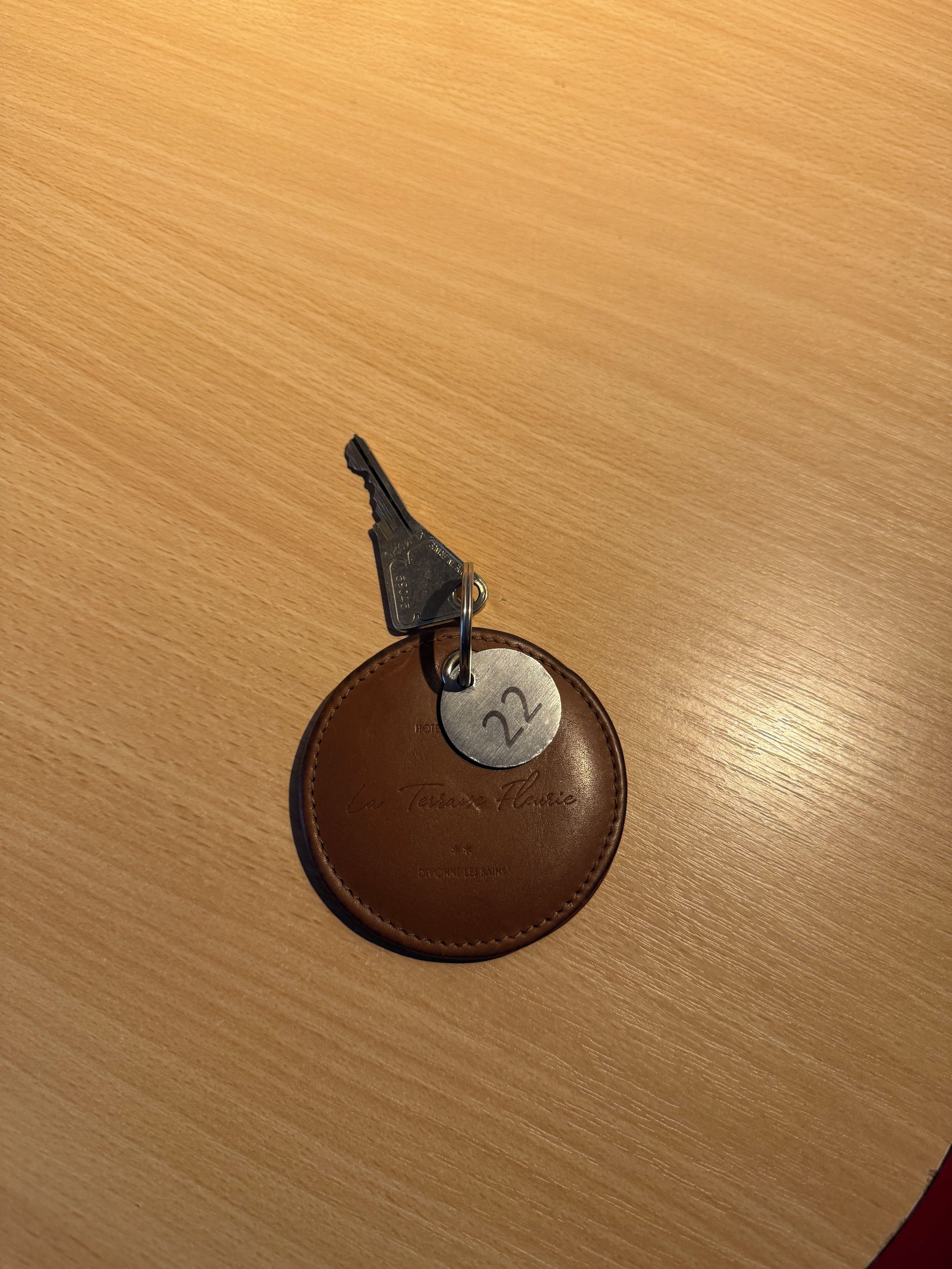 A key with a metal tag attached to a brown leather item, possibly a wallet or a key holder.