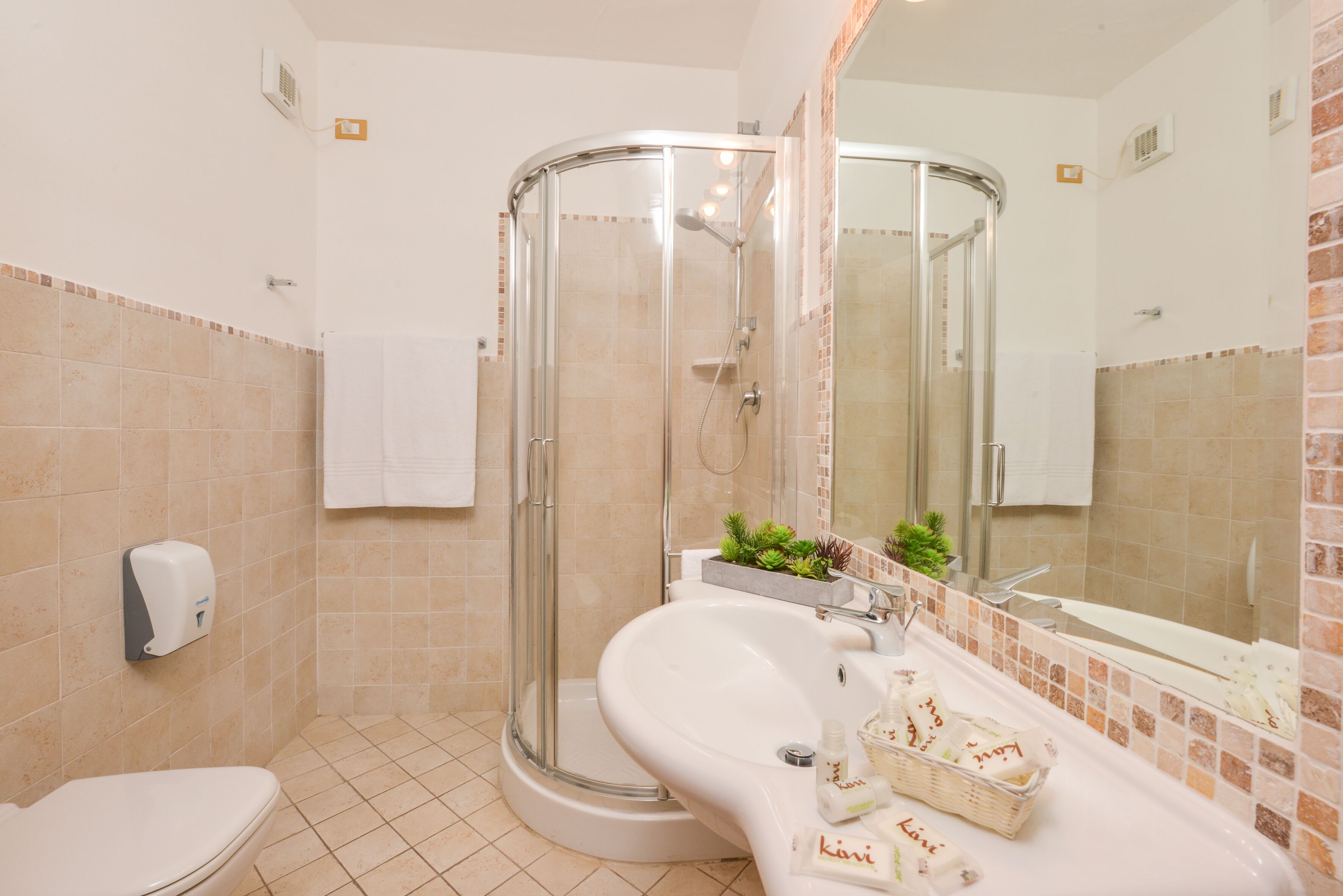 A bathroom with a glass-enclosed shower, a white sink, and a toilet.