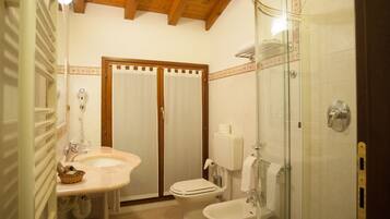 Une salle de bain avec un plafond en bois, une douche fermée par des parois de verre, un lavabo et des toilettes.