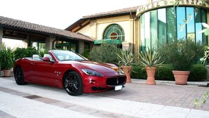 A red convertible parked in front of a hotel with a reception sign. - Hotel Corte Vecchia (San Prospero)