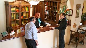 A reception desk with a wooden cabinet, a clock, and a sign indicating room rates.
