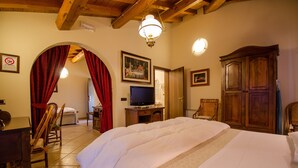A hotel room with a large bed, wooden furniture, a television, and a chandelier. - Hotel Corte Vecchia (San Prospero)