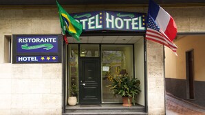 L’entrée d’un hôtel, avec une enseigne indiquant « HÔTEL » et un drapeau.