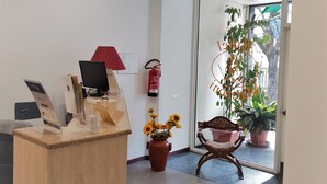 Un espace d’accueil avec un bureau en bois, une lampe rouge, un extincteur et une plante en pot.