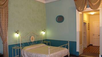 A bedroom with a single bed, a nightstand, a wall-mounted lamp, and a door leading to another room.