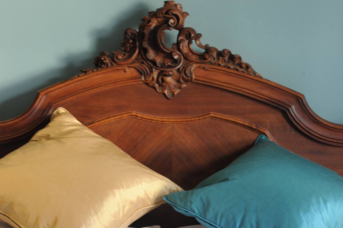A bed with a wooden headboard, two pillows, and white bedding.