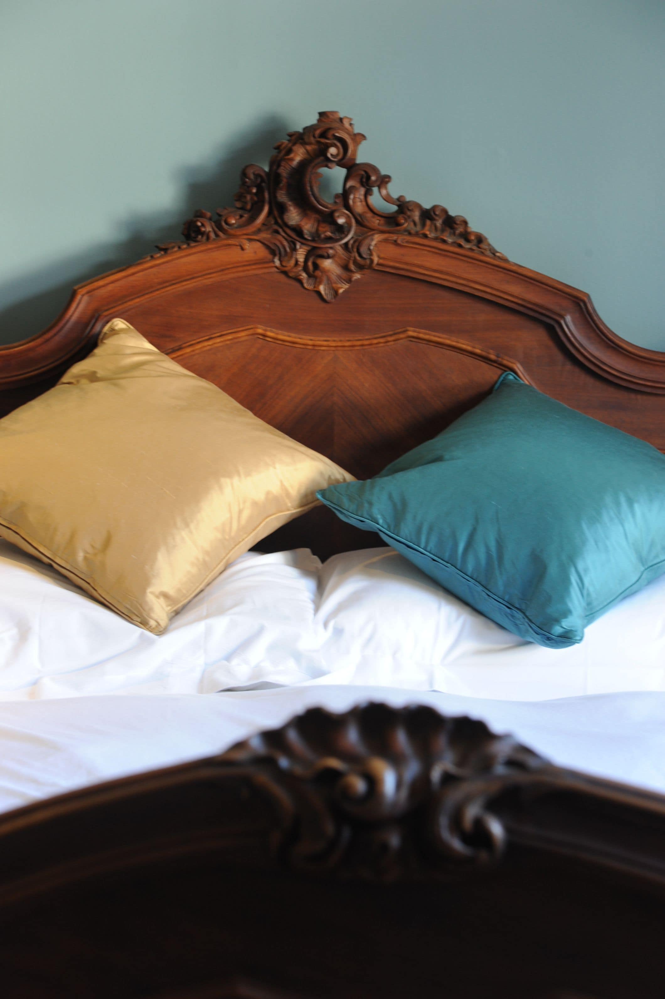 A bed with a wooden headboard and two pillows.