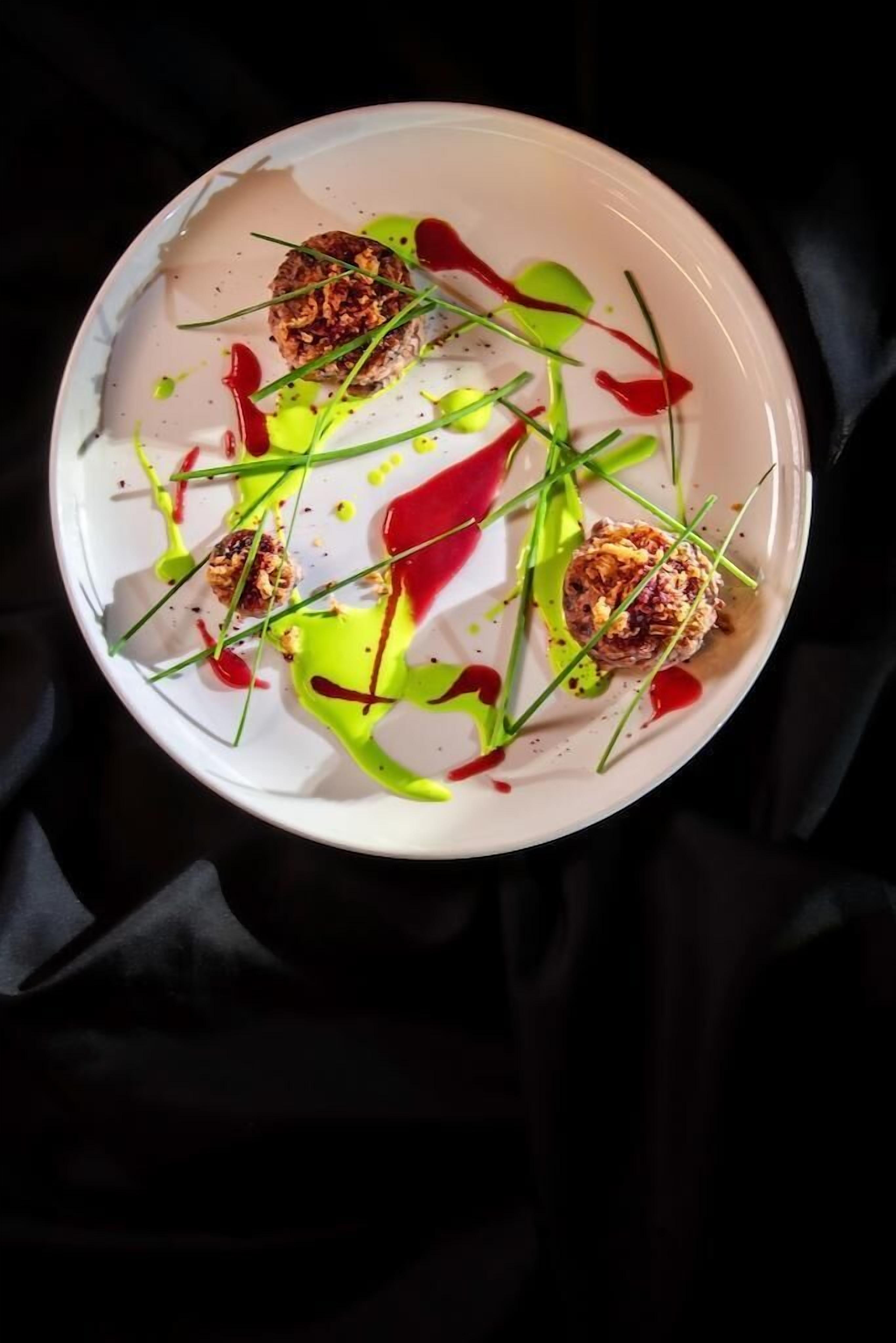 A white plate with food and sauces.