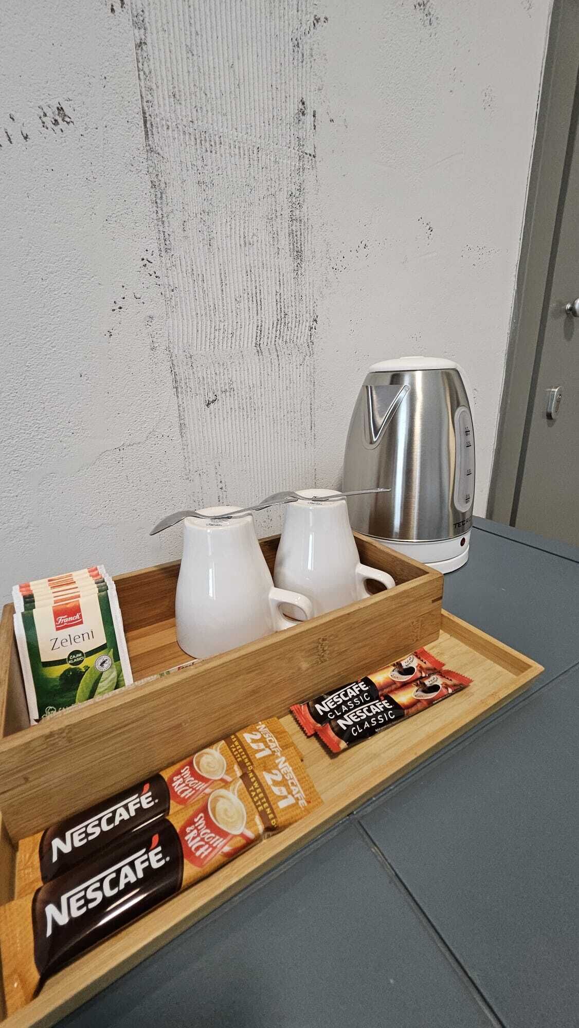 Un plateau avec deux tasses à café blanches, une dosette de café Nescafe Classic, un sachet de café Zeleni et une autre dosette de café Nescafe Classic.