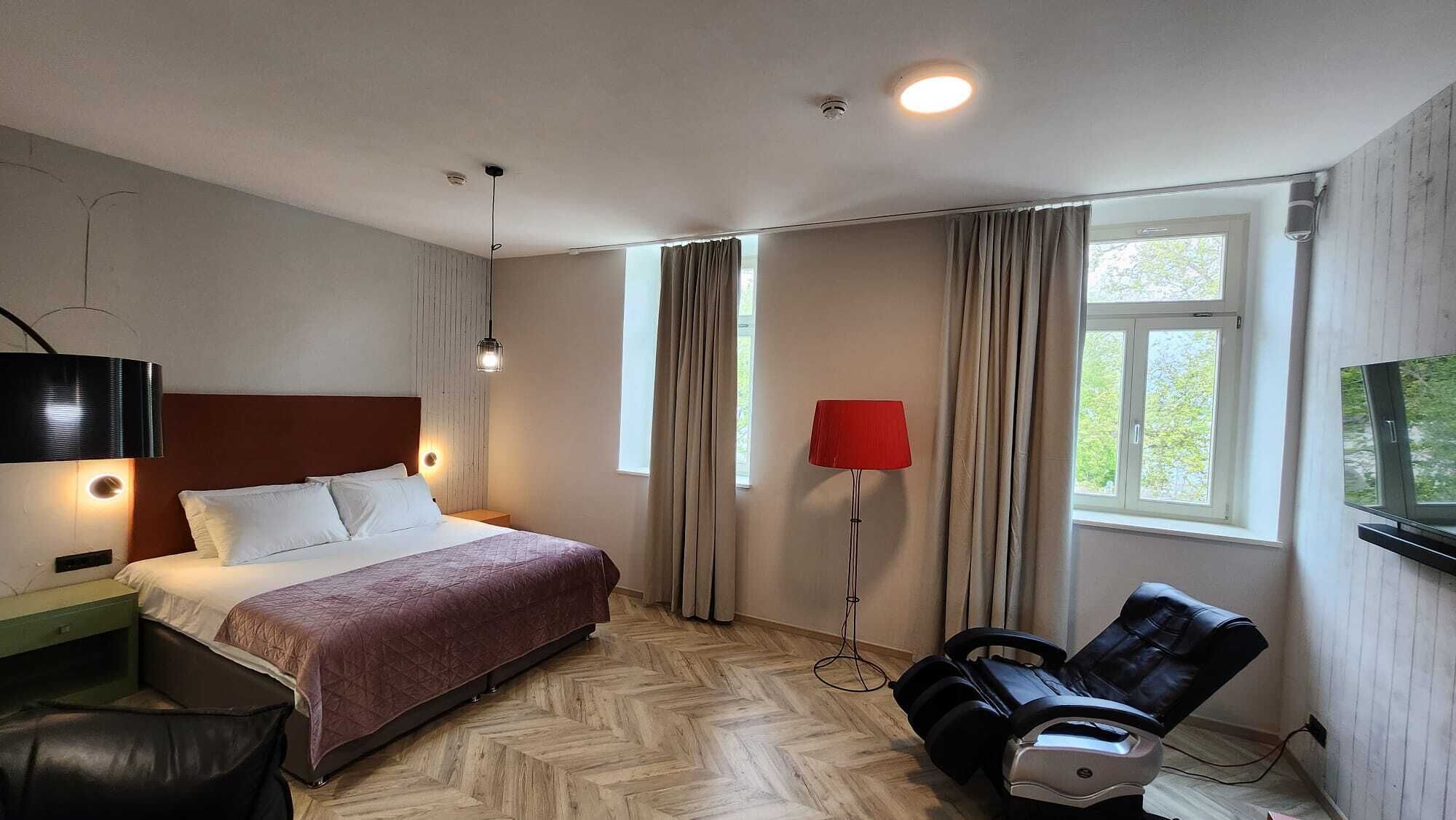 Une chambre d’hôtel équipée d’un lit, d’un bureau, d’une chaise, d’une télévision et d’un fauteuil massant.