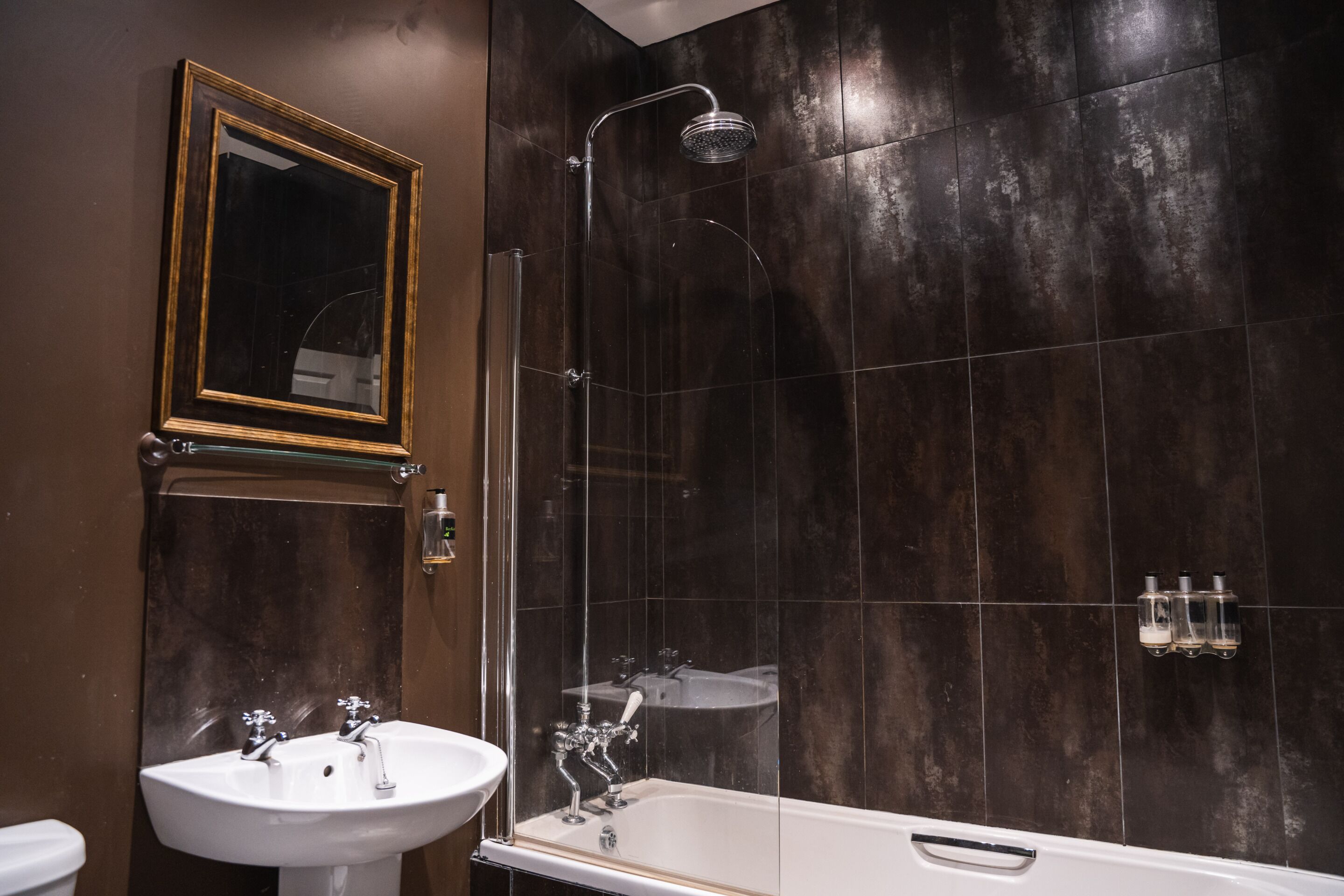 Een moderne badkamer met een bad, een douche met glazen wanden en een wastafel.