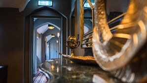 Un hall d’hôtel avec un comptoir de réception en marbre, un élément décoratif doré et une vue sur le couloir.