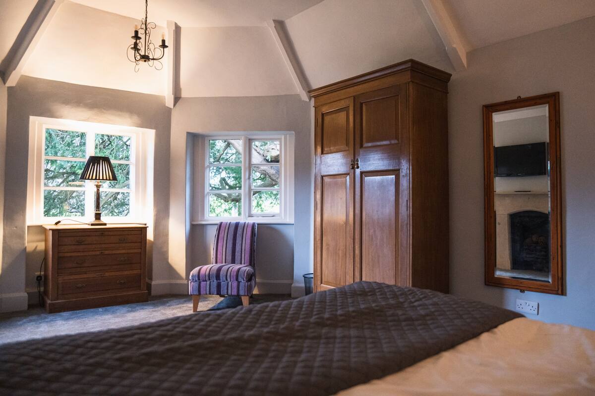 A bedroom with a large bed, wooden wardrobe, a chair, and a dresser.