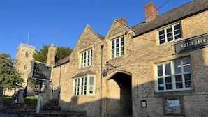 Le George Inn est un bâtiment en pierre, doté d’un style architectural traditionnel, qui se distingue par son entrée imposante et son panneau indicateur.