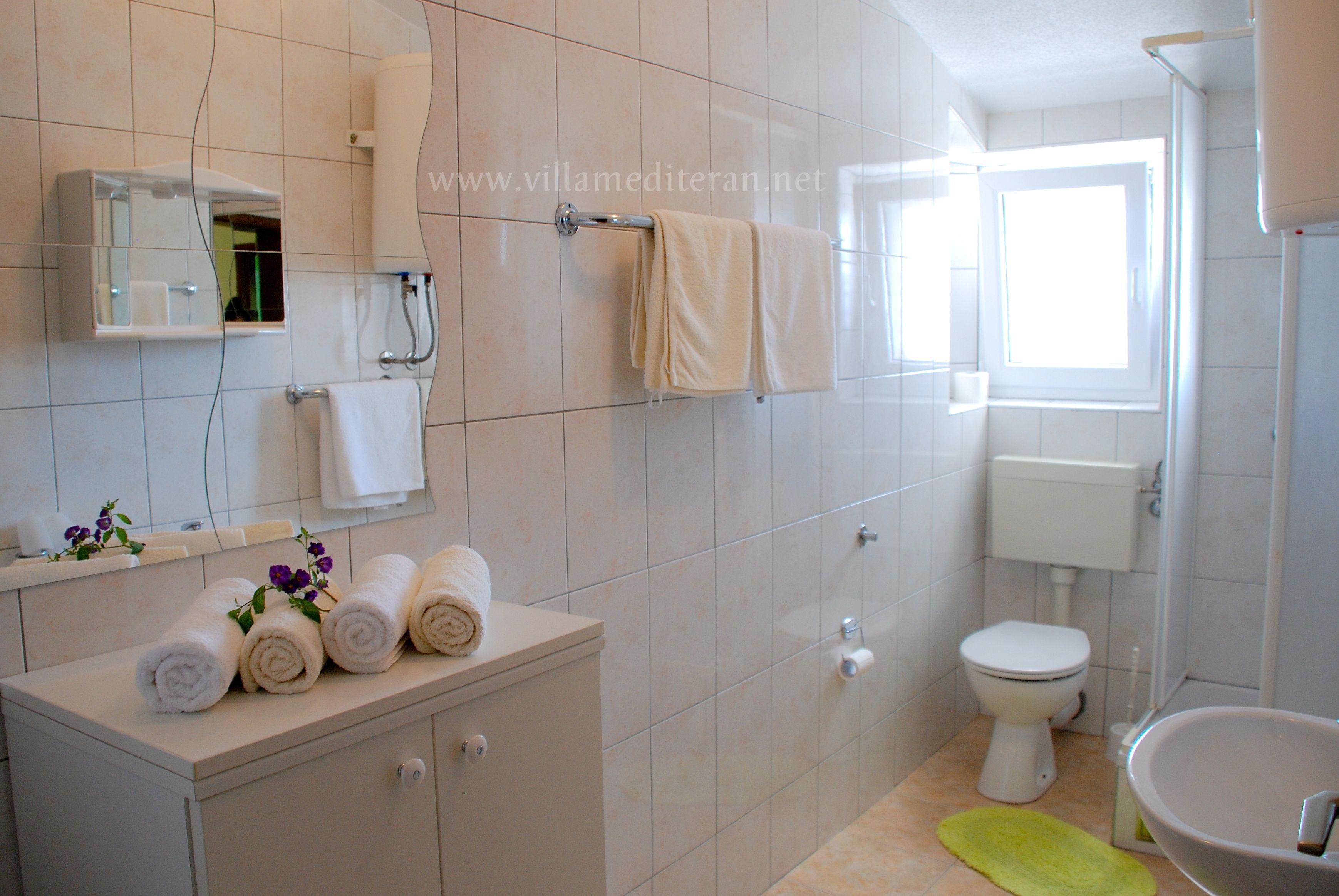 A bathroom with a toilet, sink, mirror, and towel rack.