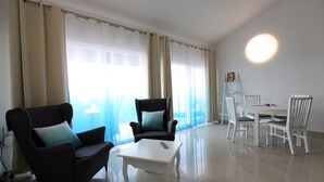 A modern living room with two armchairs, a coffee table, a dining table with chairs, and sheer curtains. - Villa Mediteran (Okrug)