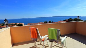 A balcony with two chairs, one with an orange towel and the other with a green towel. - Villa Mediteran (Okrug)
